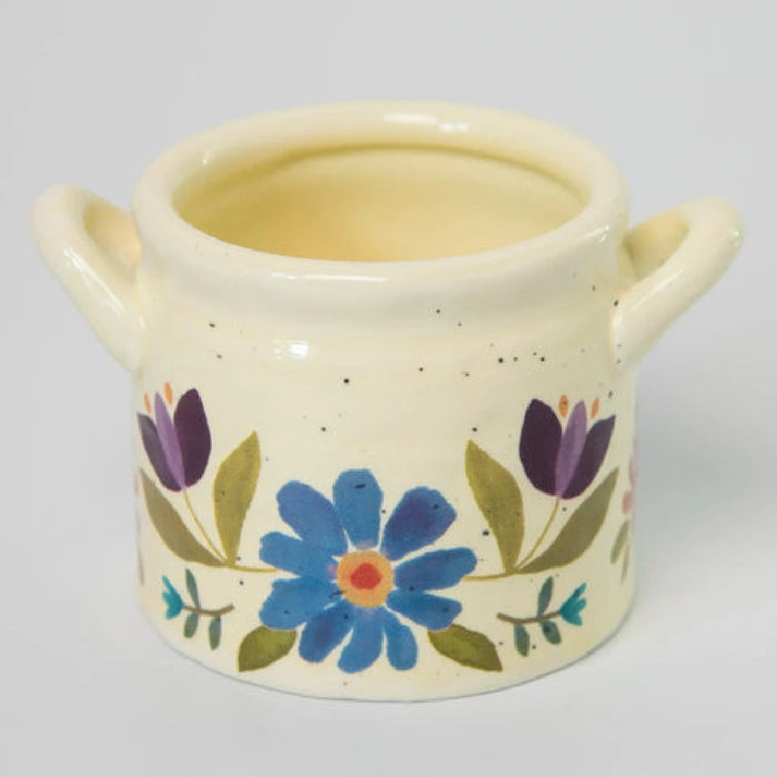 A woman is holding a small ceramic pot featuring a lush succulent plant, emphasizing her love for greenery and nature.