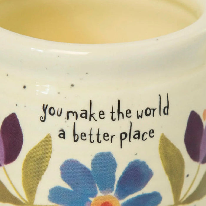 A woman presents a small ceramic pot with a thriving succulent plant, reflecting her enthusiasm for gardening and plant care.