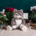 A soft, plush cat sits on a white backdrop, emphasizing its adorable design and cuddly appearance.
