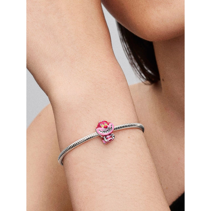 Pandora Disney Cheshire Cat Charm styled on a bracelet worn on a wrist, highlighting the charm’s vibrant pink enamel and mischievous smile.