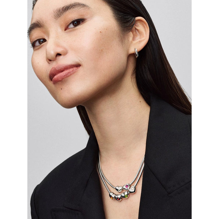 Woman wearing a necklace with heart-shaped pendants on a plain background