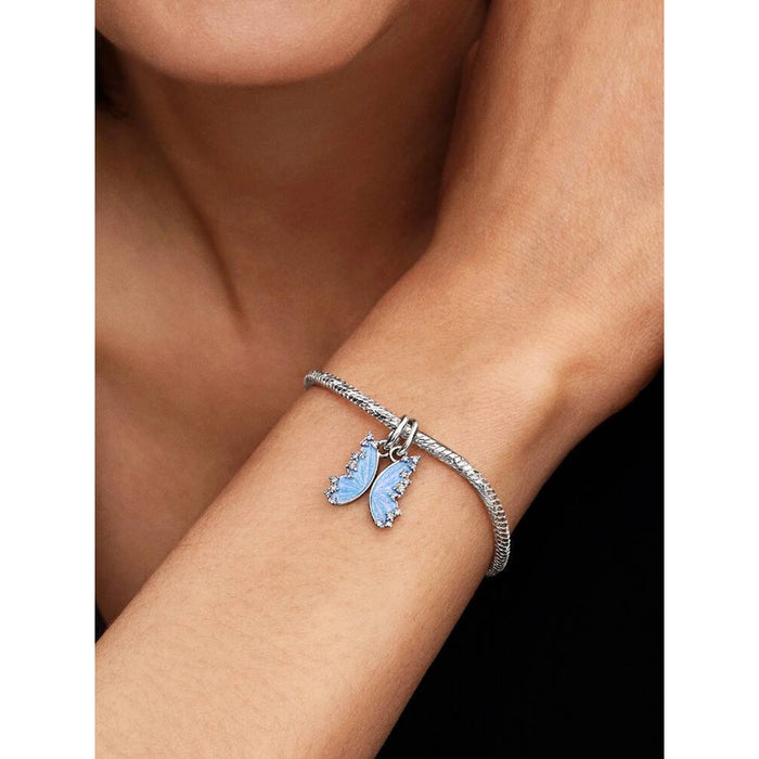 Model wearing the Pandora Splittable Butterfly Dangle Charm on a silver bracelet showcasing blue enamel butterfly wings.