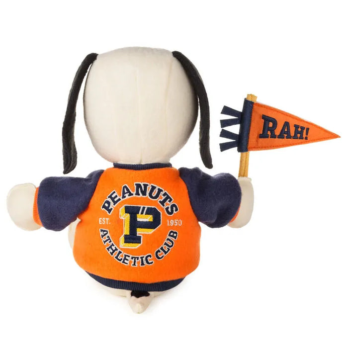 Stuffed toy resembling a dog with an orange 'Peanuts Athletic Club' shirt and a 'RAH!' flag.