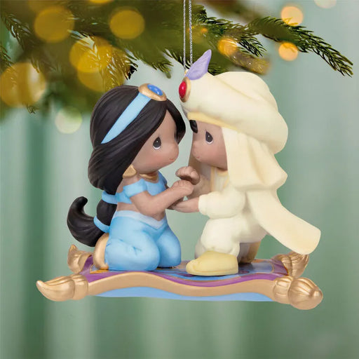 Hallmark 2026 Aladdin Jasmine ornament hanging from tree branch showing full front profile with warm bokeh lights and silver chain