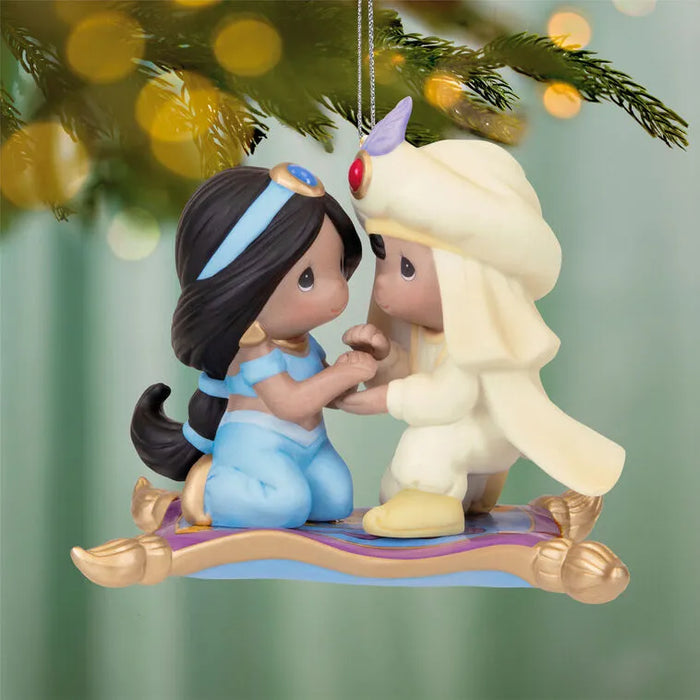 Hallmark 2026 Aladdin Jasmine ornament hanging from tree branch showing full front profile with warm bokeh lights and silver chain