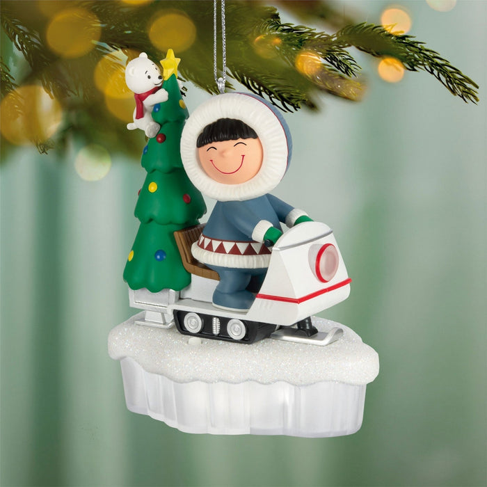 Christmas ornament of a child in an Arctic outfit with a tree and polar bear on a snowy base.