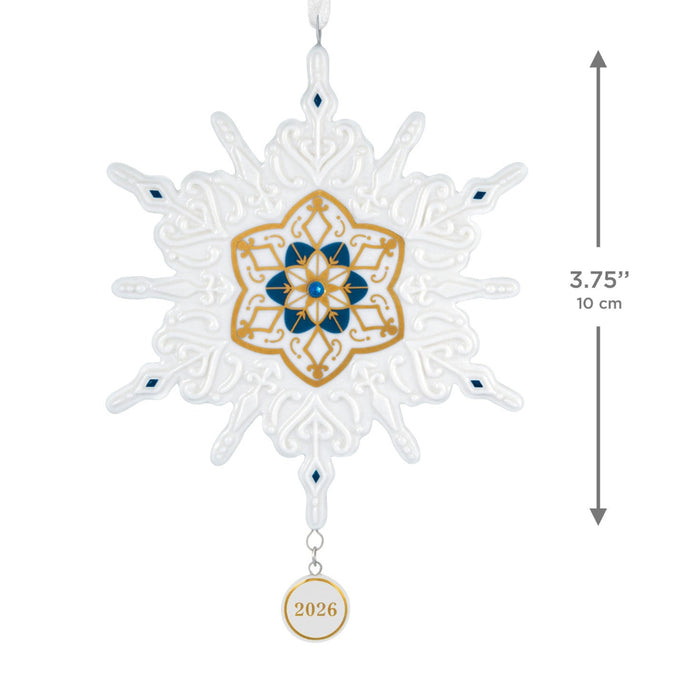 Decorative snowflake ornament with gold and blue center and '2026' tag, shown with dimensions on a white background.