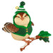 Decorative owl figurine wearing a green hat and sweater on a branch with leaves.