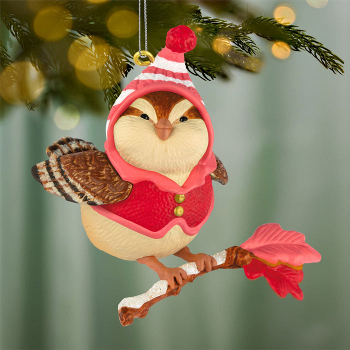 Decorative owl ornament in a red outfit hanging on a Christmas tree.