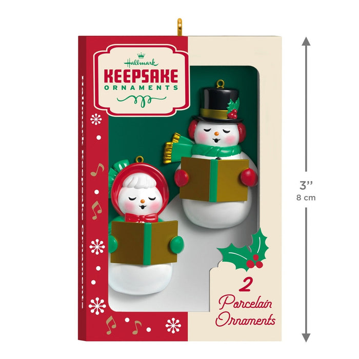 Hanging 2026 Hallmark Nifty Fifties snowman ornaments on lit Christmas tree with fireplace background