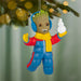 Christmas ornament of a character in winter clothing holding a snowman, hanging from a tree.