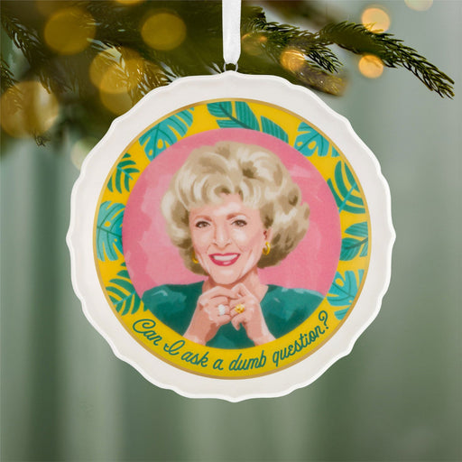 Decorative ornament with a portrait of a woman and text, hanging on a Christmas tree.