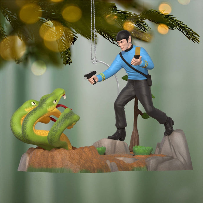 Figurine of a character in a blue shirt and black pants standing on a rock with a green snake and blurred lights in the background.