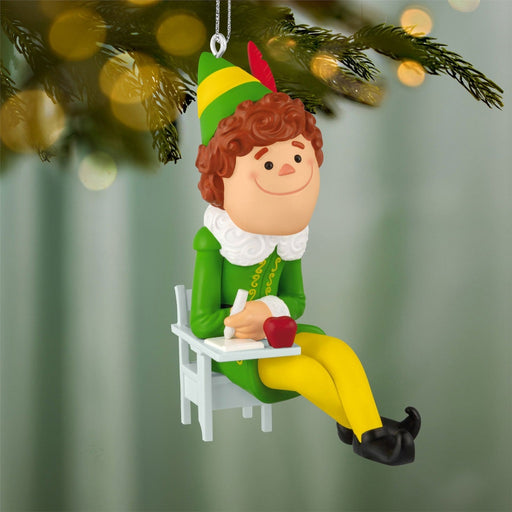 Buddy the Elf Christmas tree ornament hanging on lit pine branch with bokeh lights