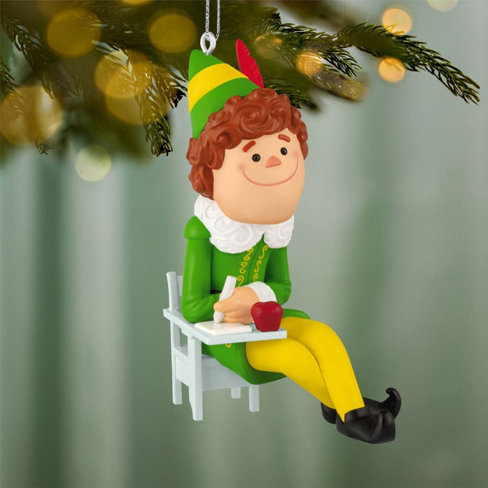 Buddy the Elf Christmas tree ornament hanging on lit pine branch with bokeh lights