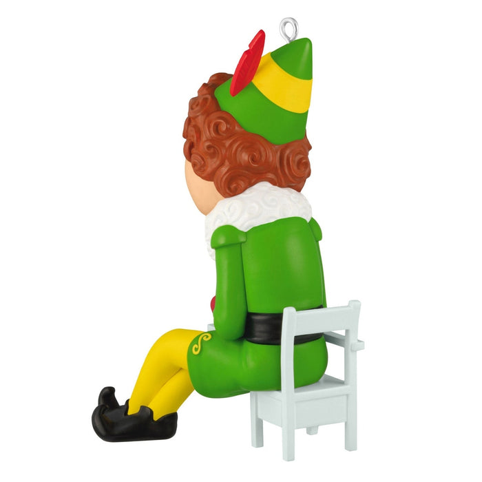 Back view of Buddy the Elf ornament showing green tunic, yellow pants, and striped hat on white chair