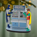 Batman Batcomputer Christmas ornament hanging on tree branch with warm bokeh lights highlighting glossy finish