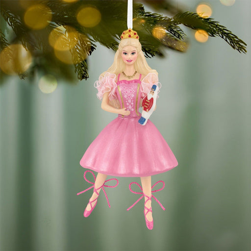 Hanging Barbie Nutcracker Christmas ornament on pine branch with warm bokeh lights
