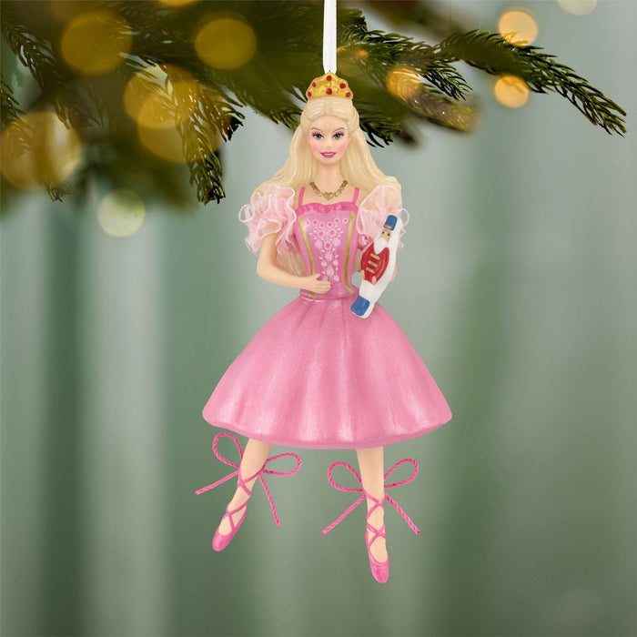 Hanging Barbie Nutcracker Christmas ornament on pine branch with warm bokeh lights