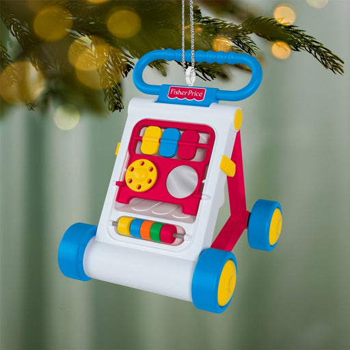 Fisher-Price Activity Walker Christmas tree ornament hanging on lit tree with warm bokeh lights