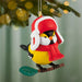Decorative bird ornament wearing a red hat and scarf on a branch with a blurred Christmas tree background.