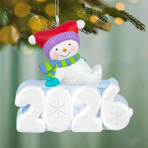 Christmas ornament with a snowman and '2021' on a blurred Christmas tree background