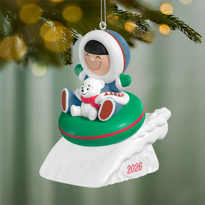 Christmas ornament with a child in a space suit and a dog, hanging on a tree.