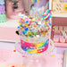 Colorful candy jar labeled 'Rainbow Candytopia' on a pink surface with pastel background