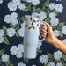 A blue tumbler with a decorative white flower design and a straw, perfect for enjoying drinks.