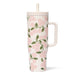 A pink and green floral print mug with a straw, featuring vibrant flowers against a light background.