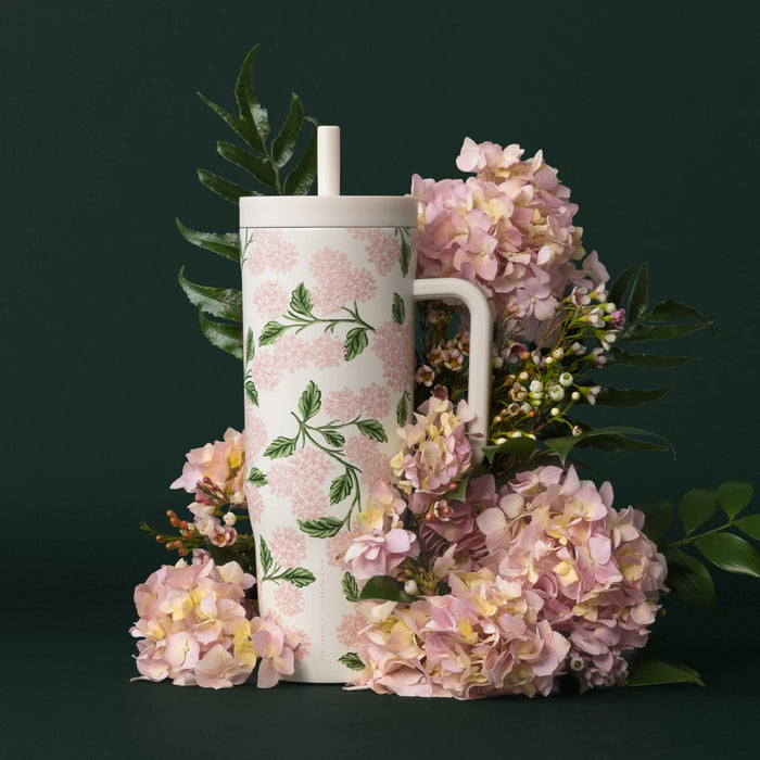 A floral mug in pink and green hues, complete with a straw, showcasing a cheerful design.