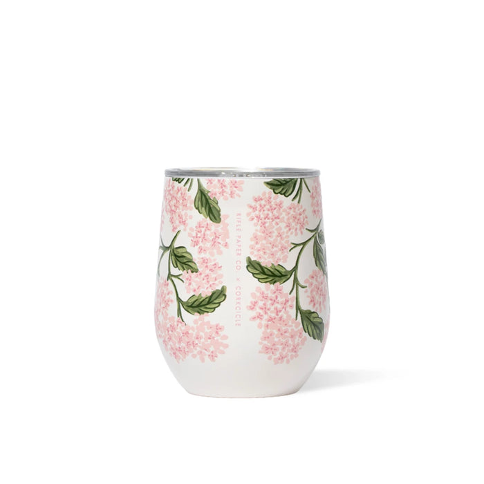 A wine glass filled with pink flowers and green leaves, elegantly arranged for a decorative display.