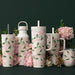 A decorative wine glass showcasing vibrant pink flowers and lush green leaves, creating a charming centerpiece.