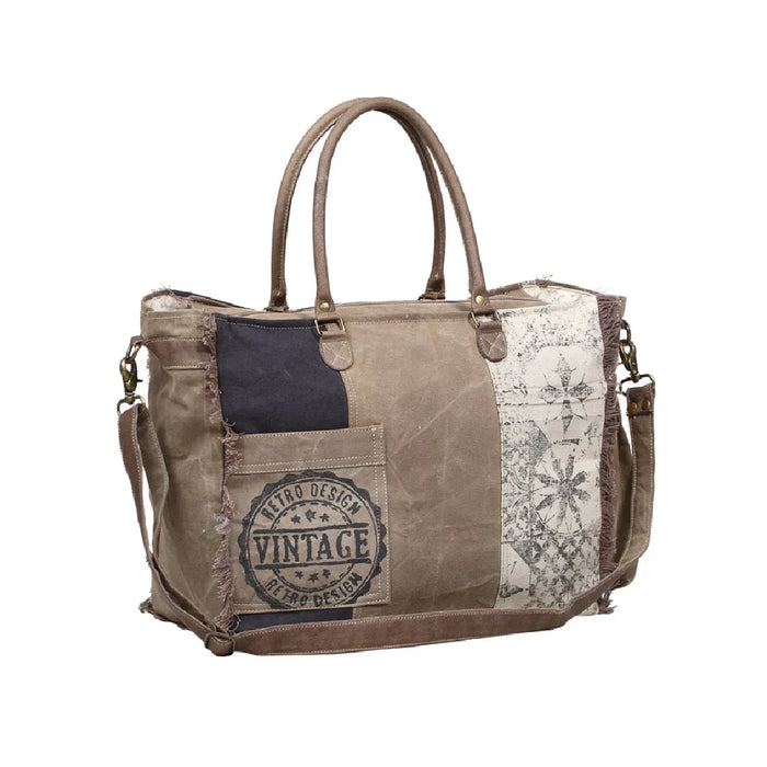 A vintage canvas bag featuring colorful patches, reflecting a retro and artistic aesthetic.