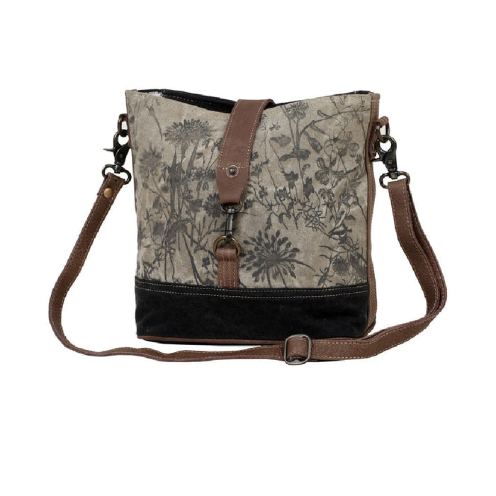 Canvas bag with a floral print, equipped with a brown strap and a brown leather shoulder strap for versatility.