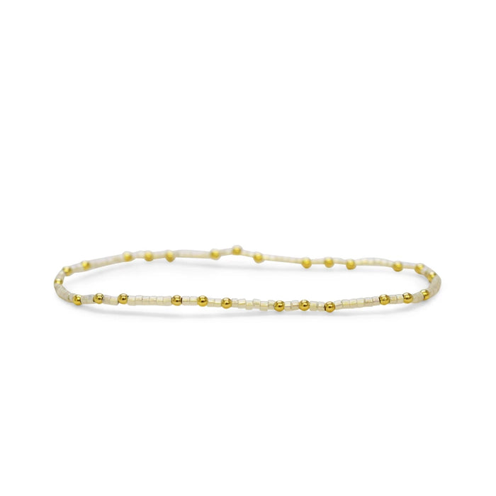 A white and gold bracelet adorned with decorative beads, showcasing an elegant and stylish design.