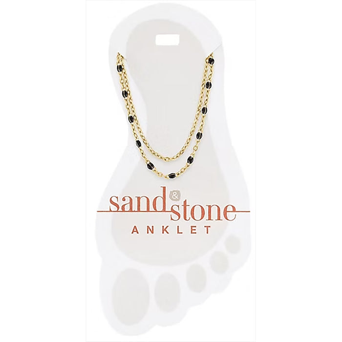 Gold and black beaded anklet on a 'sand & stone' branded card.