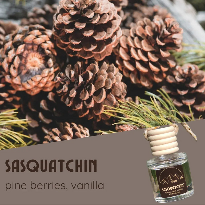 Pine cones with a bottle of Sasquatchin perfume labeled 'pine berries, vanilla'.
