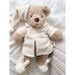 Teddy bear in a white robe on a soft, light-colored surface