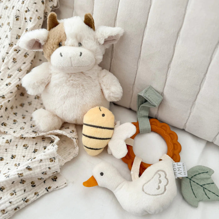 Plush cow sitting among other baby toys 