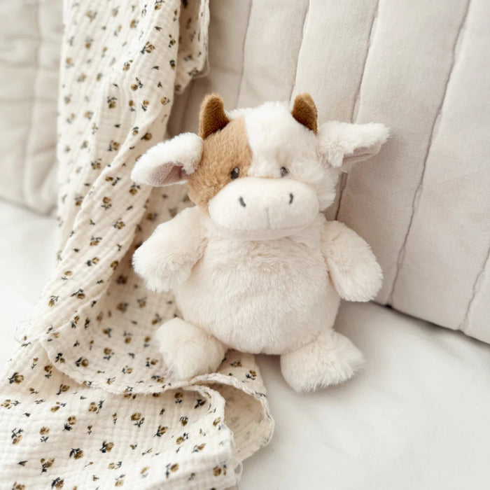 Plush cow sitting on a chair with a soft baby blanket draped behind it