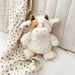 Plush cow sitting on a chair with a soft baby blanket draped behind it