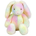 Rainbow‑colored plush bunny with pink nose, shiny eyes, and weighted bottom sitting upright on a white background