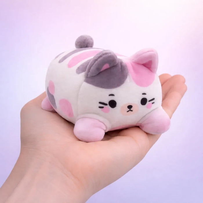 Plush cat toy held in a hand with a light purple background