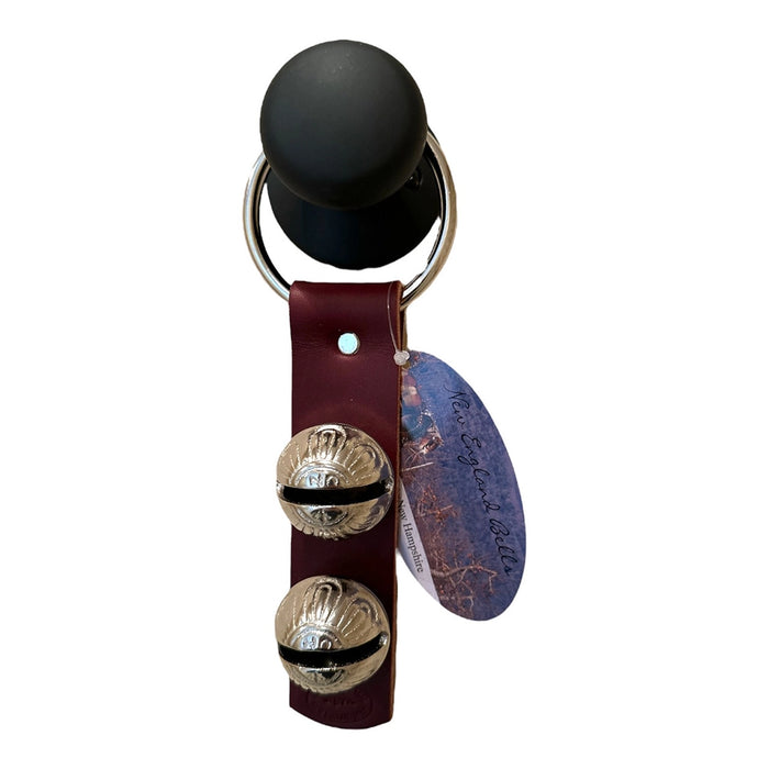 Keychain with black ball, leather strap, and metal bells on a white background