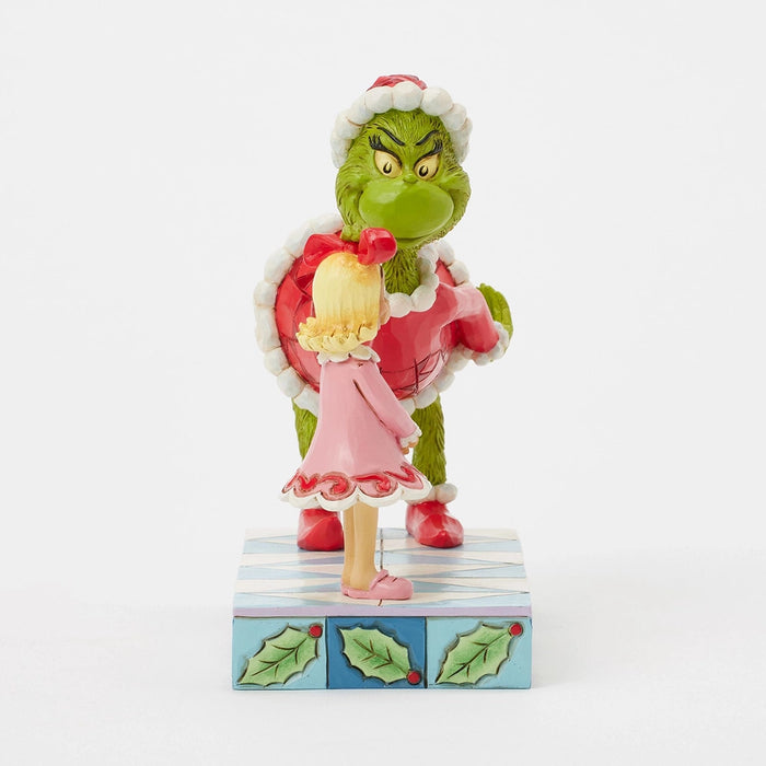 Side view of the Grinch smiling in a red Santa outfit while patting Cindy Lou’s head.