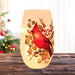 Pre-lit frosted glass vase with a single red cardinal on holly and greenery glowing on a wood tabletop.