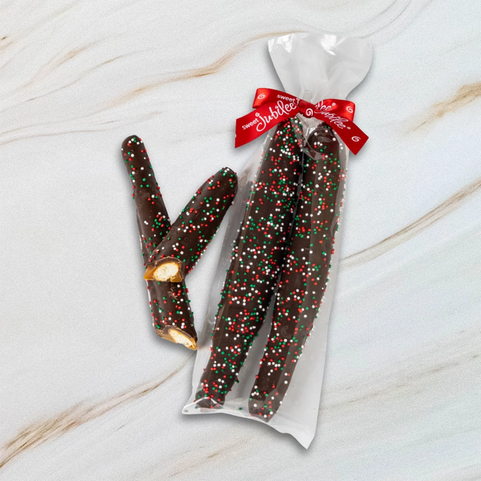 Sweet jubilee dark chocolate covered caramel Pretzel Rods with sprinkles in a clear bag with a red ribbon on a marble surface