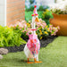 A duck wearing a colorful birthday hat stands on a green lawn, celebrating a festive occasion.