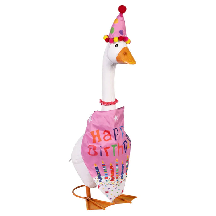 A duck in a vibrant birthday hat is perched on a lawn, adding a playful touch to a festive scene.